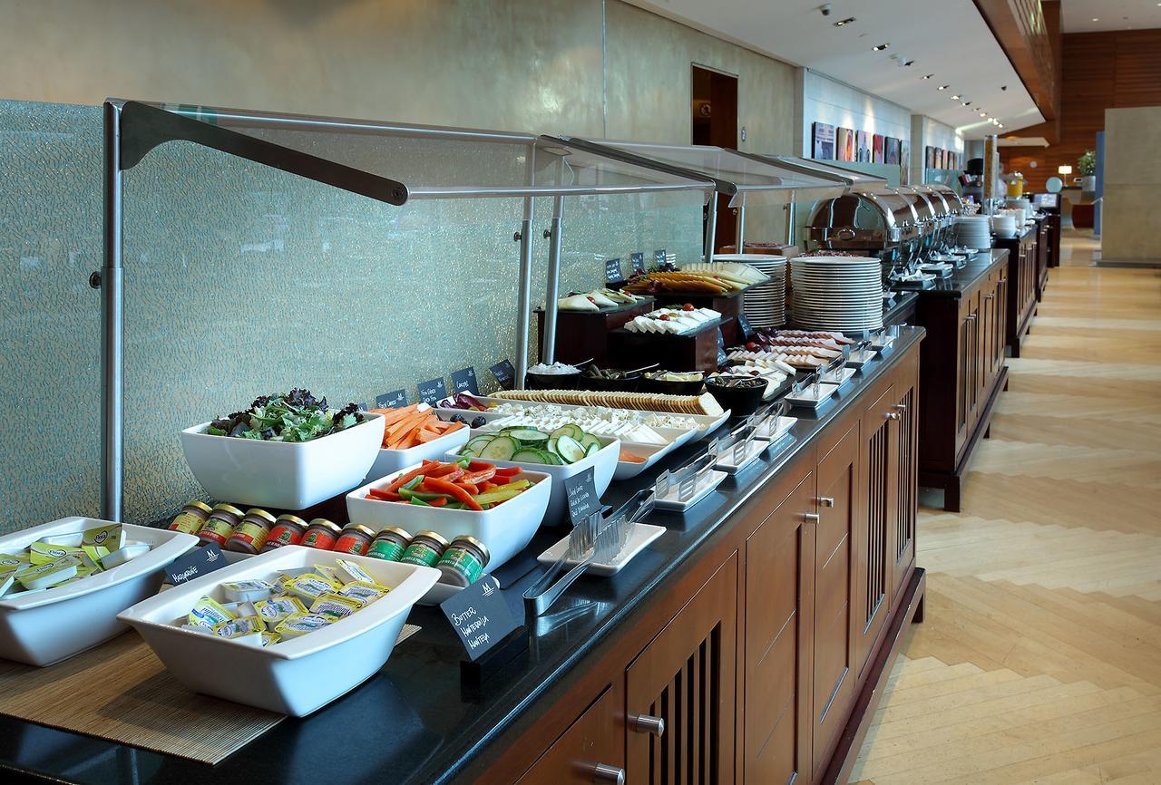 Eurostars Grand Marina Hotel Gl Barcelona Bagian luar foto The photo shows a buffet spread featuring a variety of dishes arranged along a long serving counter. There are several bowls and platters containing fresh salads, sliced vegetables, and other food items. The setting appears modern and well-organized,