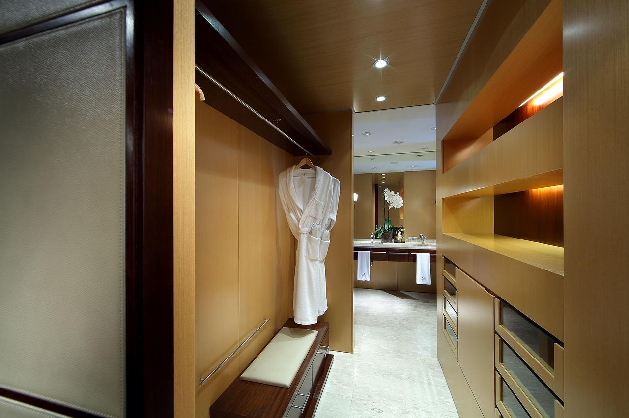 Eurostars Grand Marina Hotel Gl Barcelona Bagian luar foto The photo depicts a stylish interior space, likely a dressing area or walk-in closet. The walls are finished in warm wood tones, creating a modern and elegant atmosphere. A white robe hangs on a sleek hook, and there is a bench next to it. The area i
